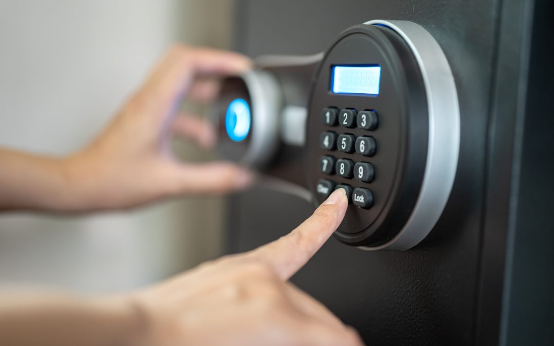 Hands entering a code on a digital safe's keypad with a display screen.